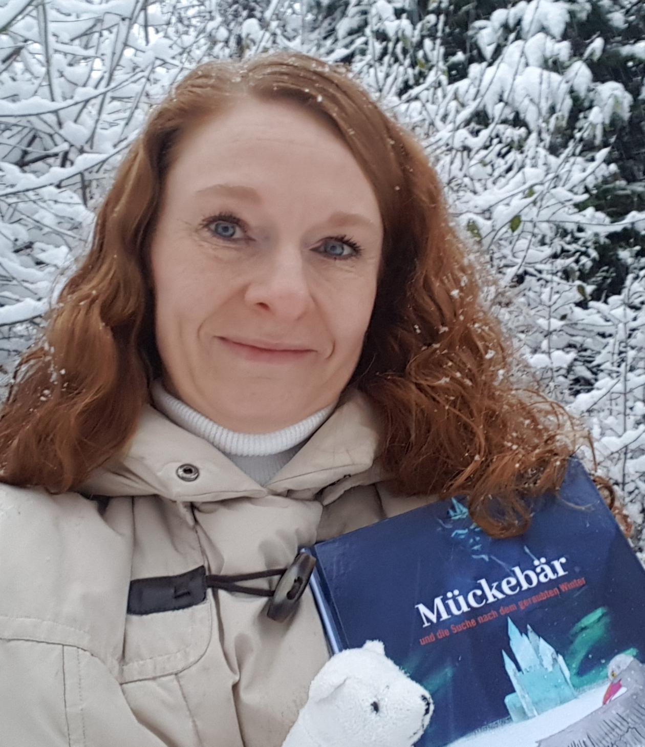 Die Autorin hält ihr Buch im Arm und steht im Schnee